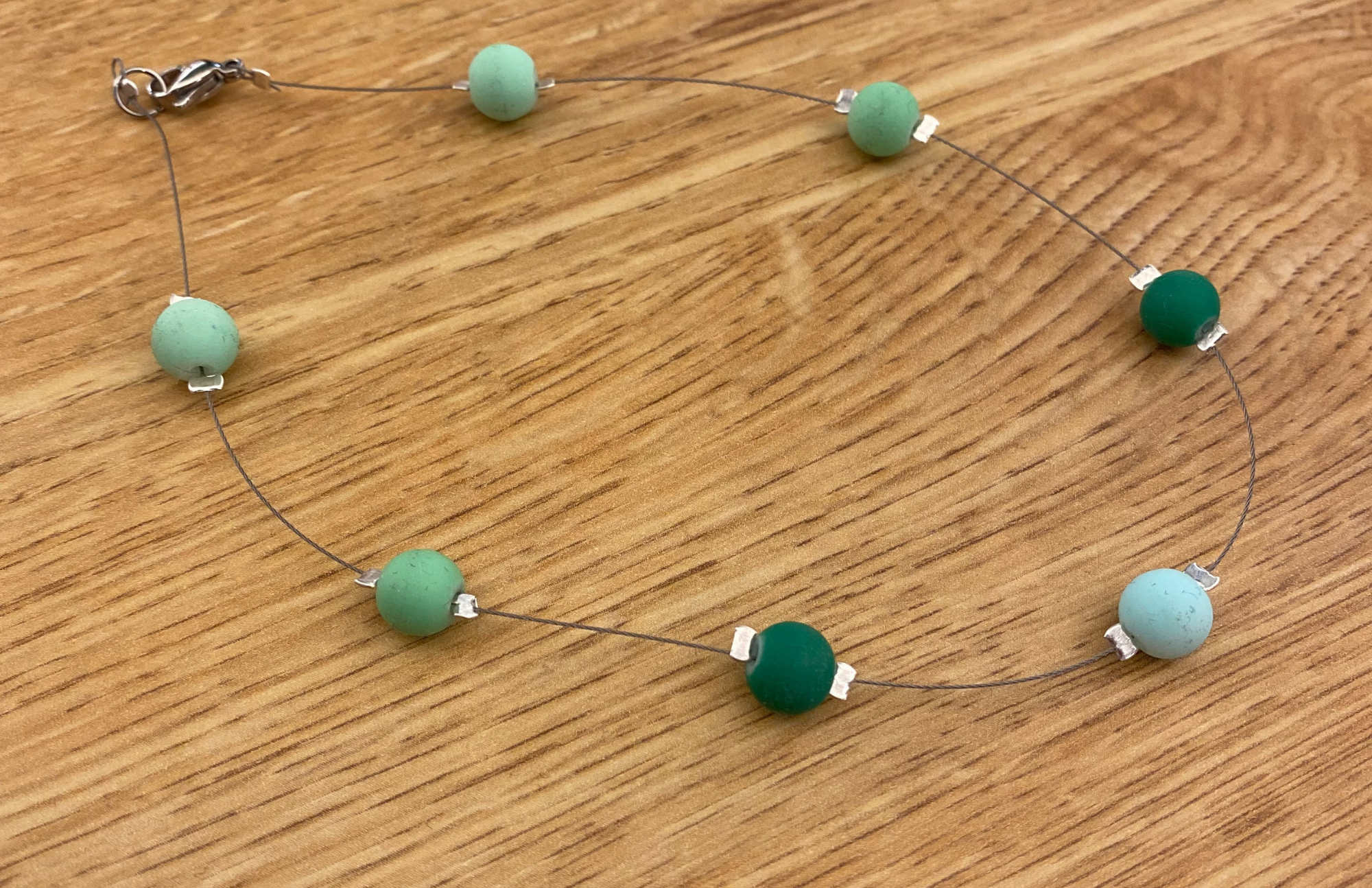 Green beads spaced out on a necklace for a floating look