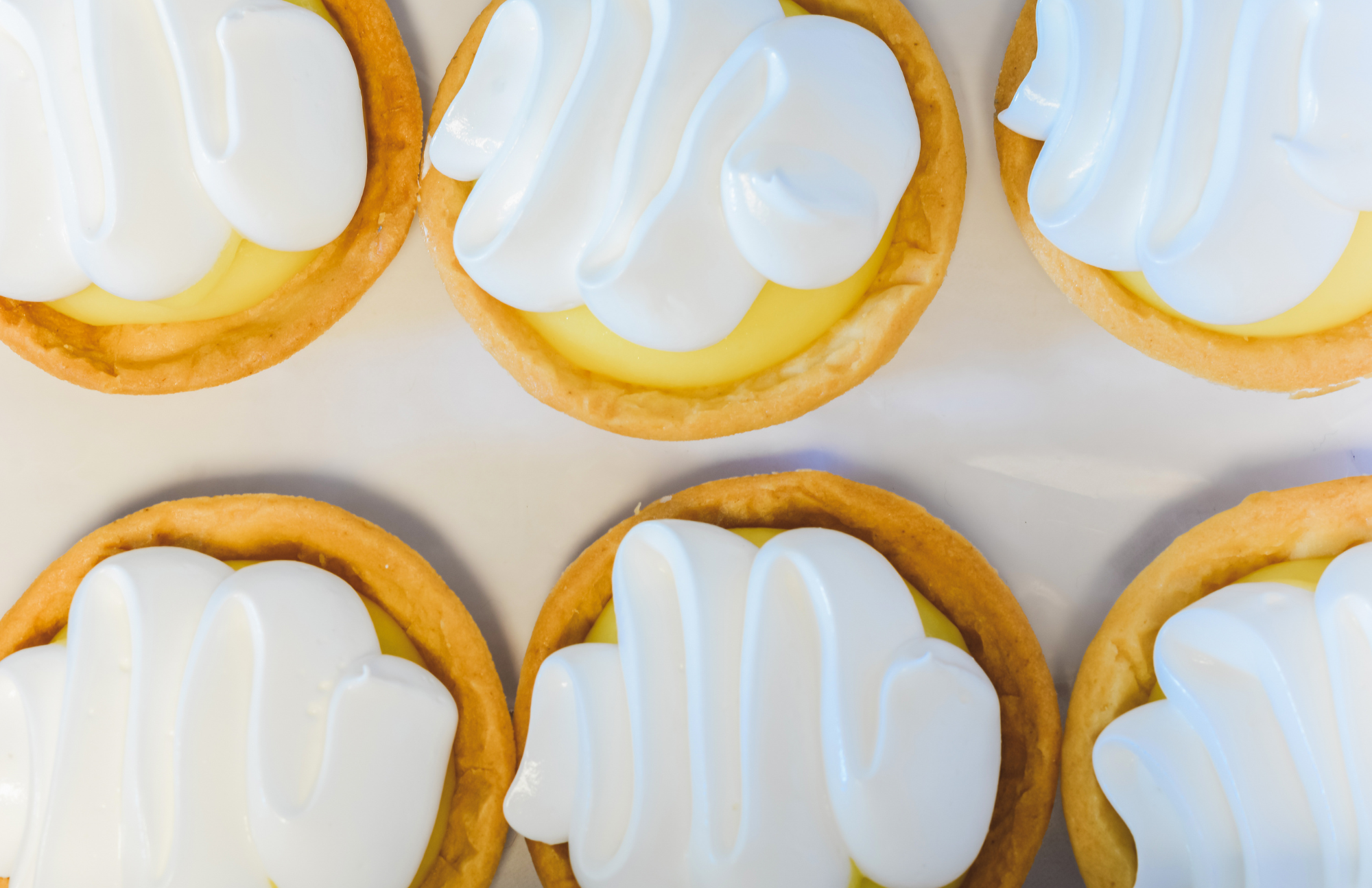 six delicious looking mini lemon pies with whipped cream