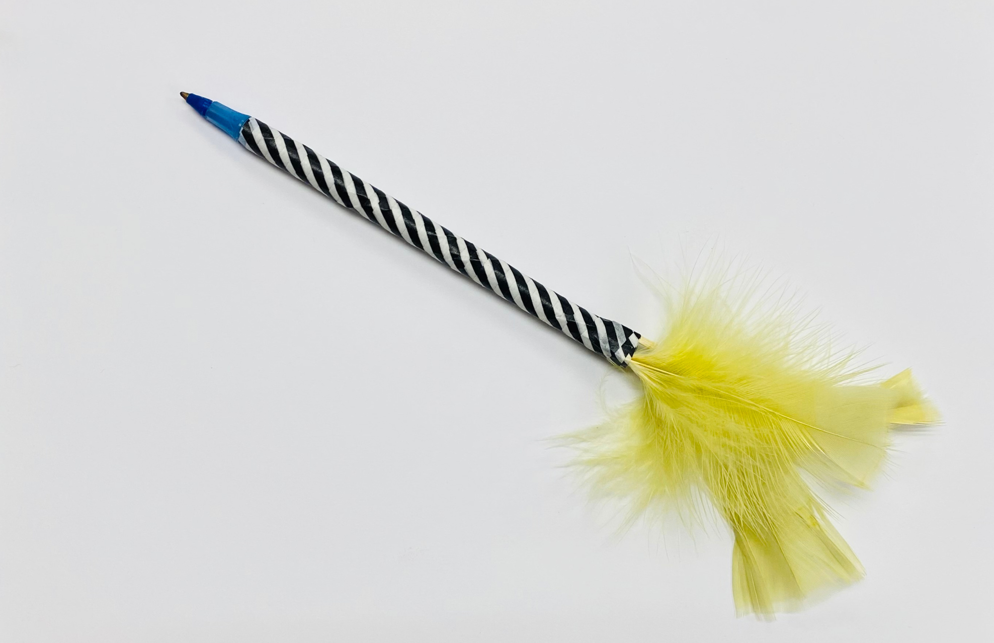 Pen wrapped in black and white washi tape with yellow feather at the tip