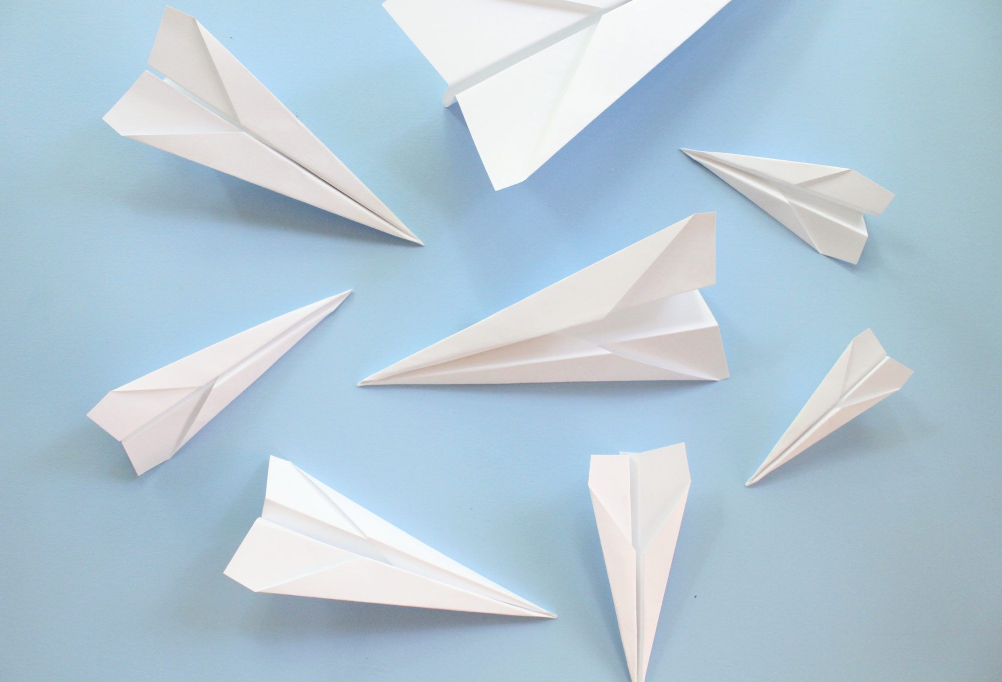 Various sized paper airplanes on a blue background