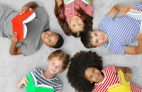 Children laying on ground in a circle, all reading books