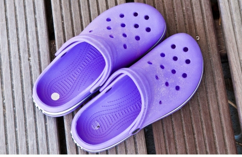 Pair of purple croc shoes on a wooden background