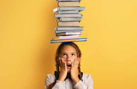 Child with braids balancing a stack of books on their head