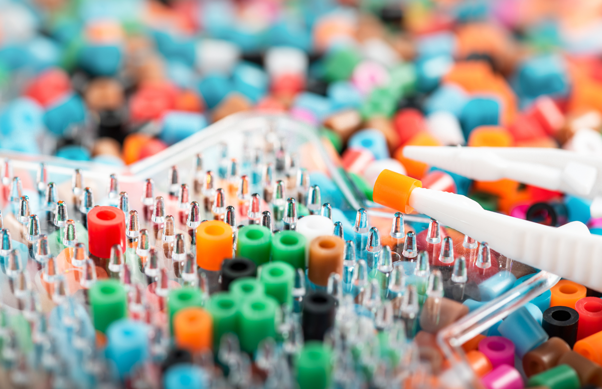 Close up of multi colored perler beads, with clear star shaped peg board and tweezers