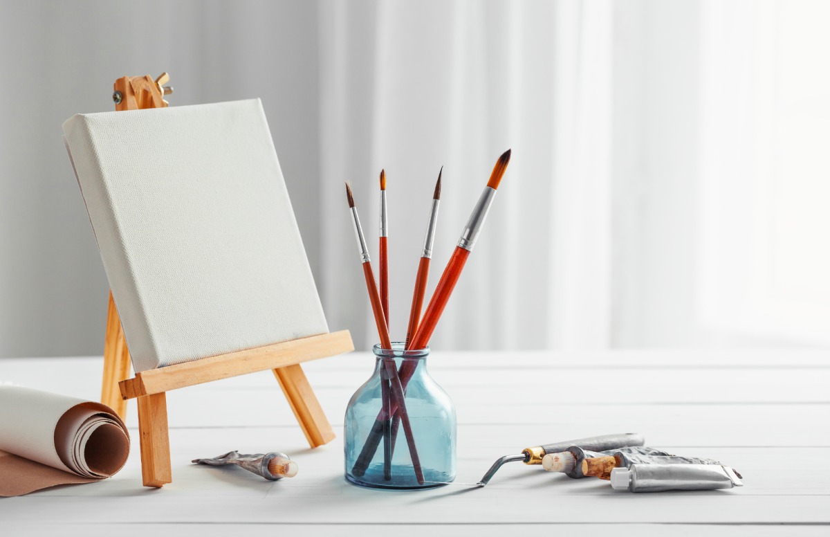 Paint canvas set up with paintbrushes and paint on a table