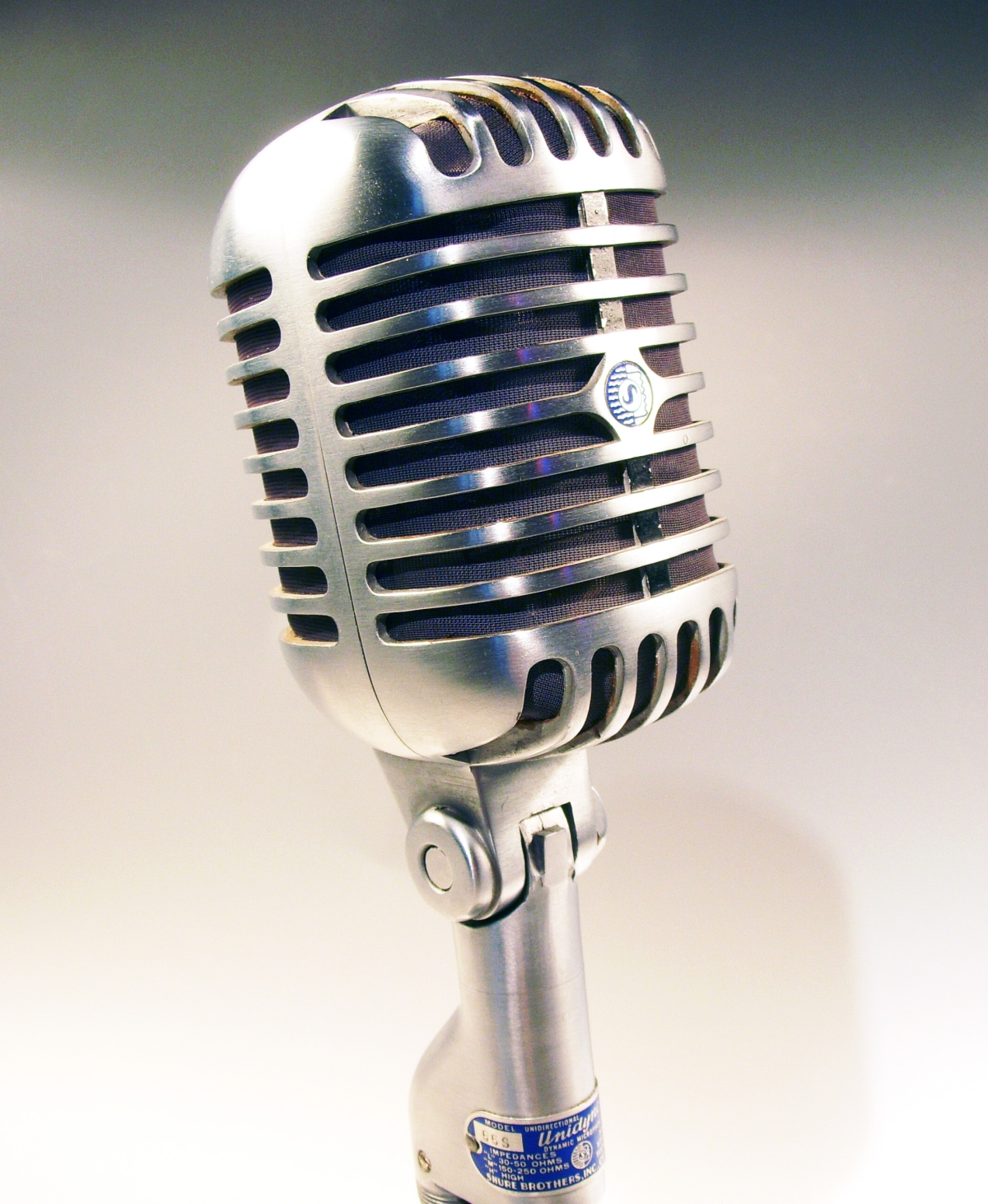 A silver microphone in front of a grey gradient background